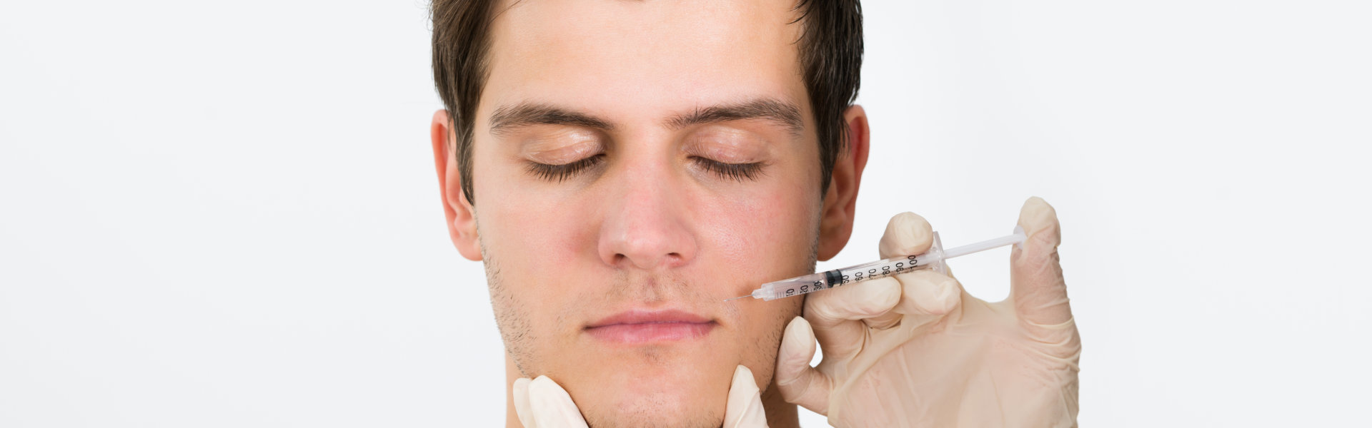 Close-up Of Doctor Hands Injecting Botox Injection In Man Face